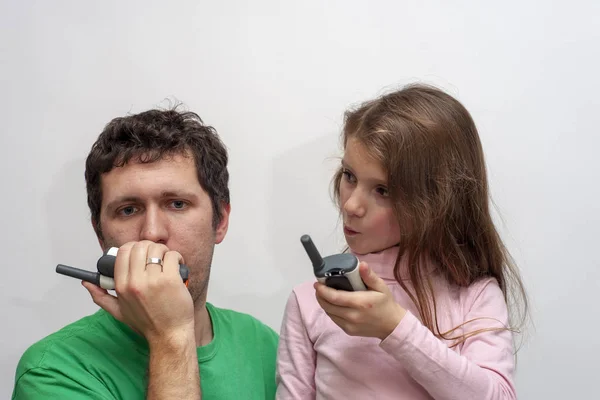 The little girl speaks by a walkie-talkie with dad on a white background isolated. Concept of communication, speaking, playing.