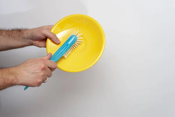 The man's hands are cleaning up by dish brush on a white background.