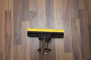 Yellow mop on a wooden floor. Cleaning, vanish dirty.