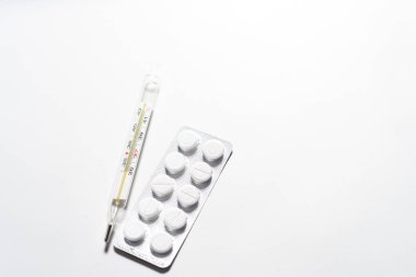 Pills and thermometer on white background isolated.