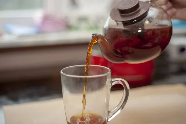 Pouring black tea into a mug from a teapot. Breakfast, morning, aromatic tea.