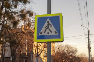 Sonbahar şehrinde gökyüzü ve ağaçların arka planında yayaların kesiştiğine dair işaretler.