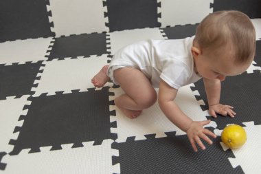 Siyah-beyaz arka planda sarı limonlu, beyaz kumaşlı bebek..