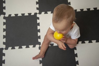 Siyah-beyaz arka planda sarı limonlu, beyaz kumaşlı bebek..