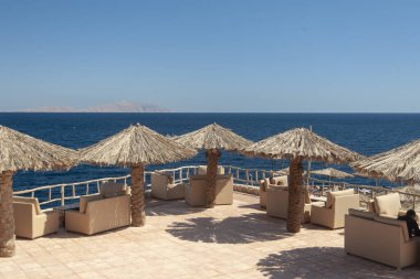 Denizin arka planında Thatched plaj şemsiyeleri.