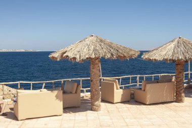 Denizin arka planında Thatched plaj şemsiyeleri.