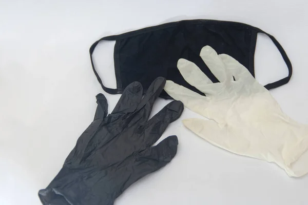 Black medical mask and black and white medical gloves. Isolated on white. Concept of coronavirus and COVID-19.