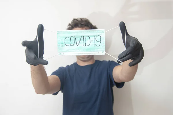 The young man with a medical mask in black nitrile medical gloves isolated on white. Concept of stop virus, COVID-19, and illnesses, keep a distance.