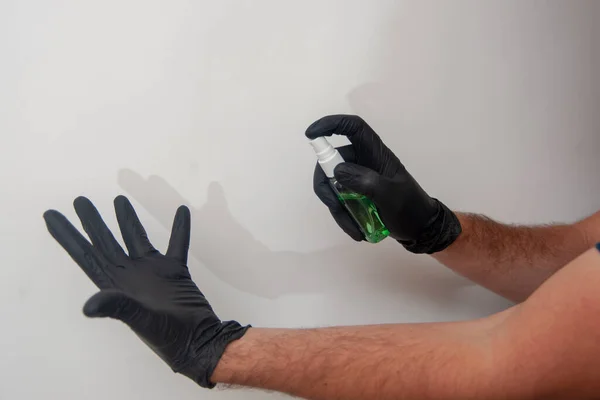 Hand disinfection by sanitizer. Humans hands in black nitrile gloves.
