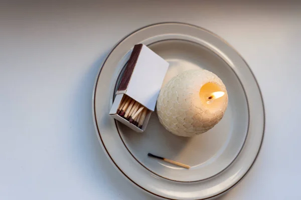 Copy space of burning a round candle and box of matches.