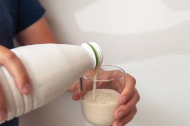 Erkek eli bardağa yoğurt döküyor..