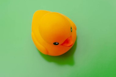 Yeşil arka planda oyuncak turuncu plastik ördek. Üst görünüm.