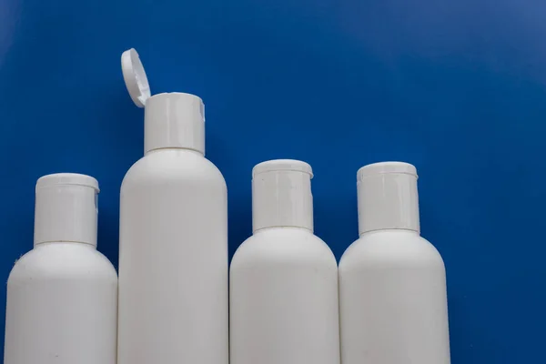 White bottles on blue background. One of the bottles is up than others. Concept of dissent, not like others, talking about something, freedom of speech, speaking.