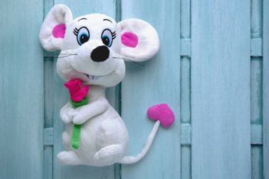 yumuşak oyuncak beyaz fare açık mavi ahşap torba üzerinde mor bir gül
