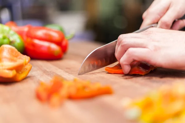 Matlagning. närbild av manlig hand skära peppar på skärbrädan hemma — Stockfoto