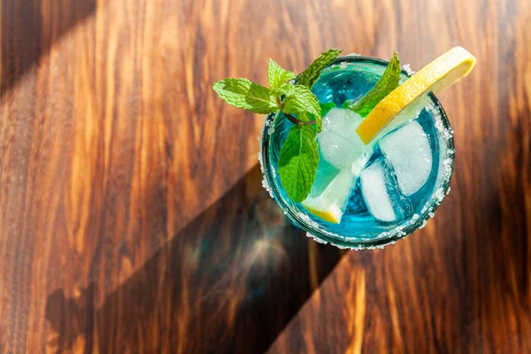 Solo Cóctel alcohólico azul en una copa en un mostrador de bar de madera — Foto de Stock