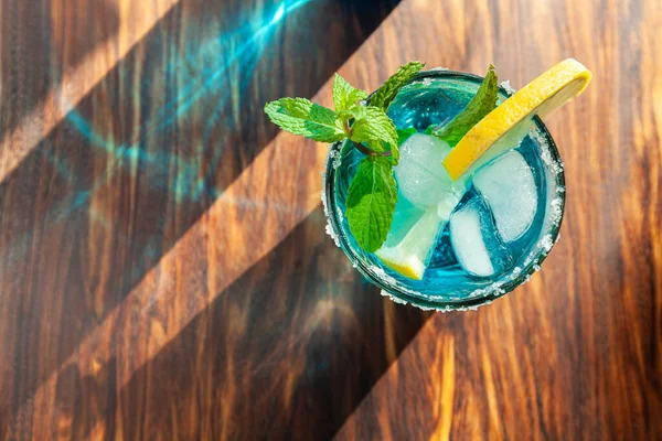 Coquetel alcoólico azul em um copo em um balcão de madeira — Fotografia de Stock