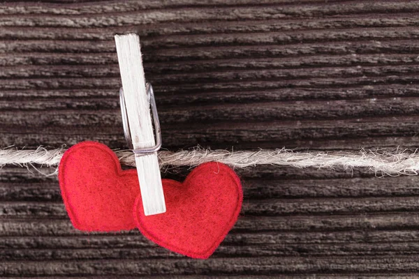 Twee rode textiel harten hangen aan een touw op houten pagina — Stockfoto