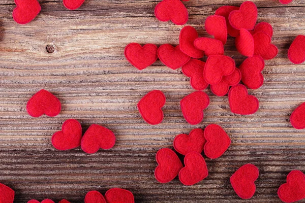 Malé červené textilní srdce na dřevěné pozadí — Stock fotografie