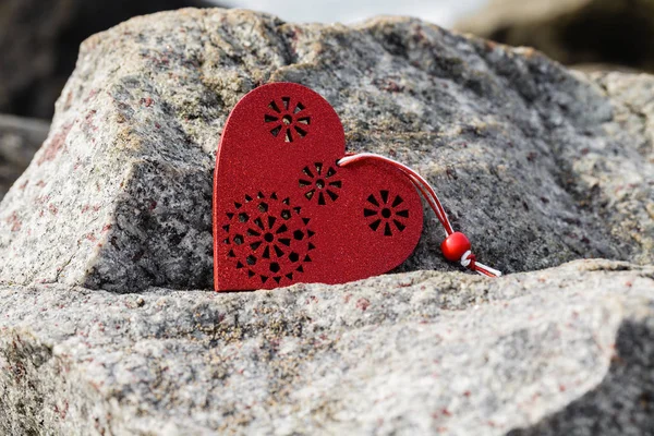 Símbolo de coração de madeira vermelho deitado na pedra . — Fotografia de Stock