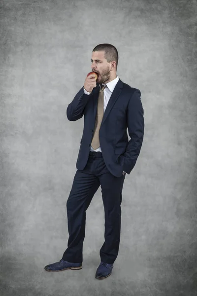 Joven hombre de negocios guapo comiendo una manzana — Foto de Stock