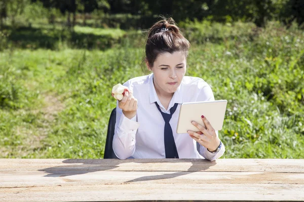 专注的商务女人吃苹果和阅读邮件 — 图库照片