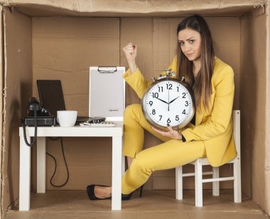 ufak bir ofiste oturan bir saat tutan bir iş kadını