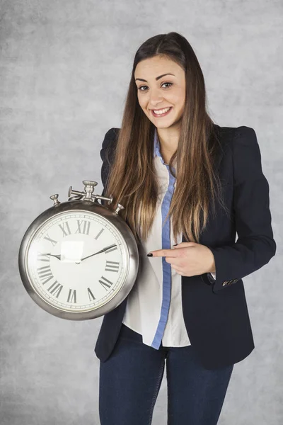 Glad affärskvinna som pekar på en timme — Stockfoto