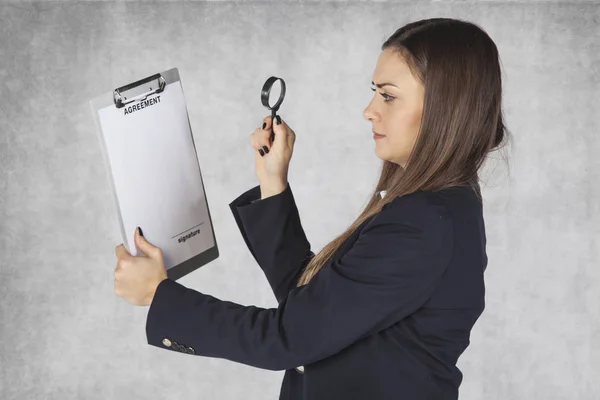 Бізнес-леді використовує збільшувальне скло, щоб прочитати угоду — стокове фото