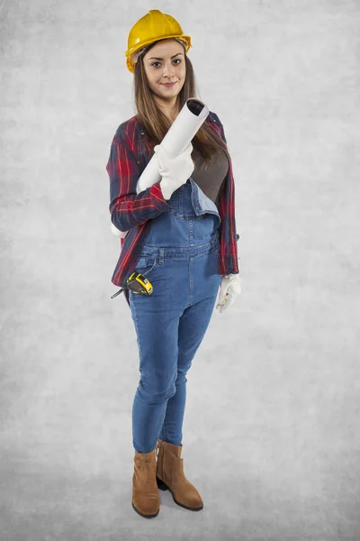 Female construction worker poses for photo, plans in hand — Stock Photo, Image