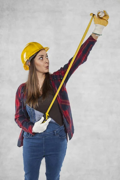 Женщина-строитель растягивает метр, удивленное лицо — стоковое фото