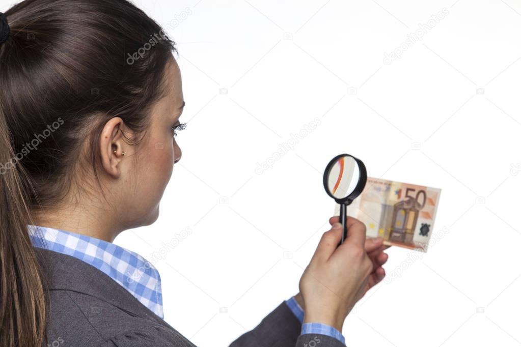 Young business woman checks the authenticity of money on white b