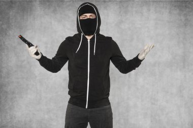 Maskeli hırsızın elinde bir silahla