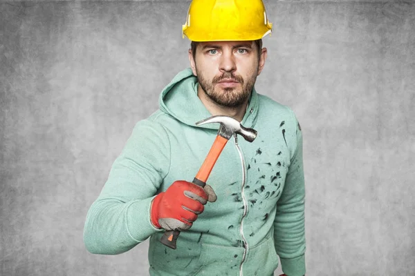 Een gevaarlijke werknemer houdt een hamer in zijn hand — Stockfoto
