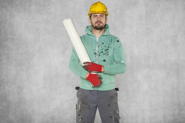 Pracovník vede stavební plány na rameni — Stock fotografie