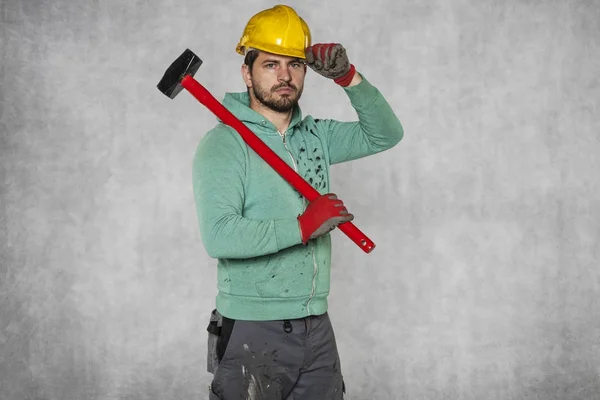 Gelukkig werknemer met een hamer op zijn schouder en een helm op zijn h — Stockfoto