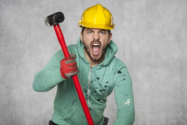 Um trabalhador com um martelo grande grita como um homem possuído — Fotografia de Stock