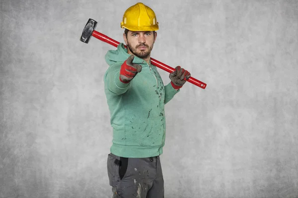 Een werknemer met een grote hamer op zijn schouder, wijst u — Stockfoto