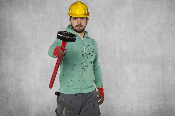En arbetstagare med en stor hammare ser på kameran — Stockfoto