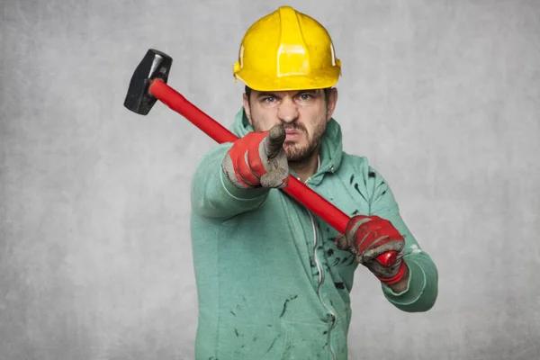 Um trabalhador com um grande martelo, aponta para você — Fotografia de Stock