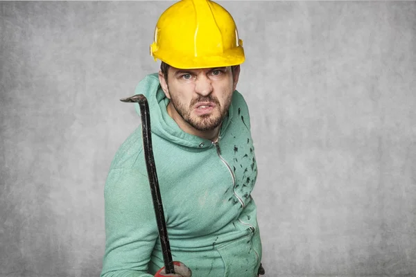 An angry worker holds a crowbar in his hand — Stock Photo, Image