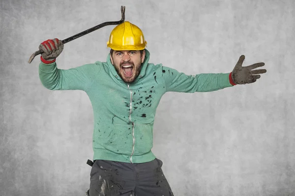 Een gekke werknemer raakt een breekijzer met een veiligheidshelm — Stockfoto