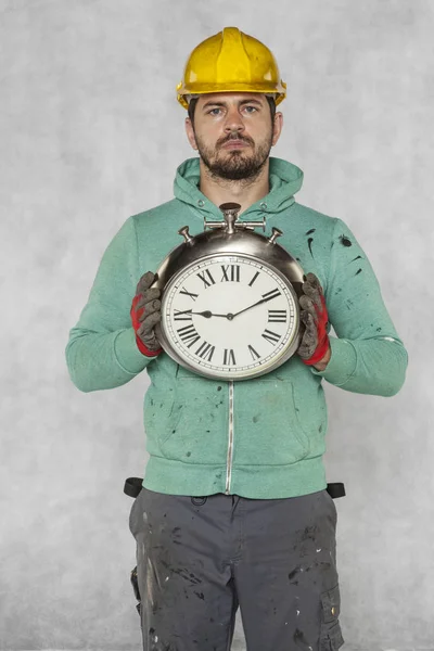 The concentrated worker keeps the clock in front of him — Stock Photo, Image