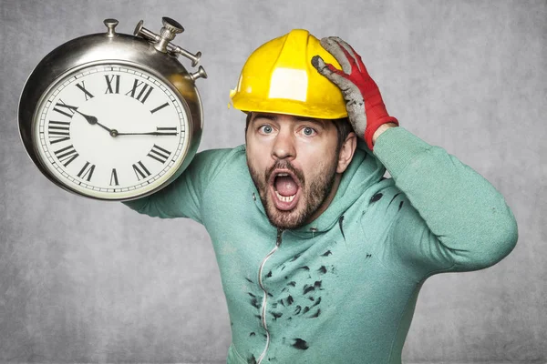 Překvapený pracovník drží hodiny v ruce — Stock fotografie