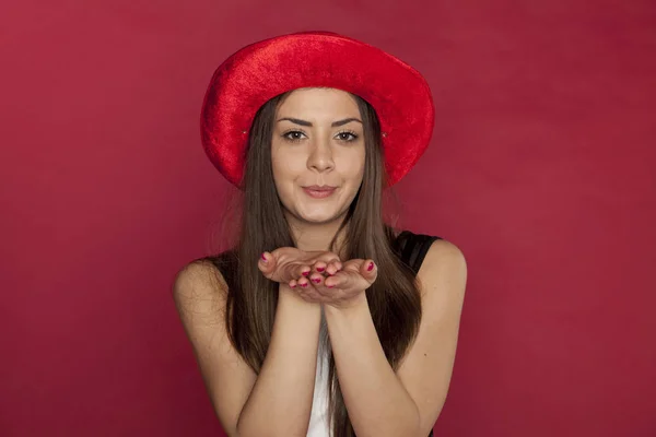Mooi meisje in de rode hoed stuurt kussen — Stockfoto