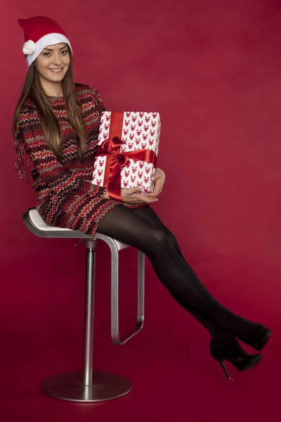 Piękna kobieta siedzi na krześle, trzymając prezent na Boże Narodzenie — Zdjęcie stockowe