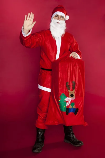 Santa golfte zijn hand, die een zak vol cadeaus — Stockfoto