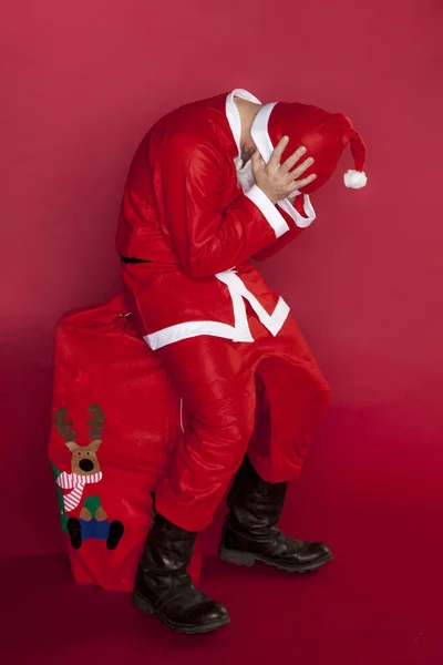 Kaputte Weihnachtsmänner sitzen auf einer mit Geschenken gefüllten Tüte — Stockfoto