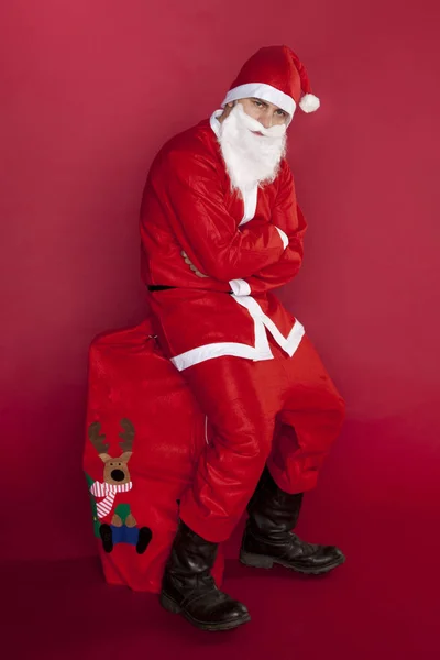 Infeliz Santa Claus está sentado en una gran bolsa llena de regalo — Foto de Stock