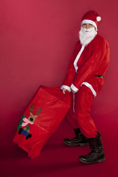 Santa Claus is het dragen van zware presenteert — Stockfoto